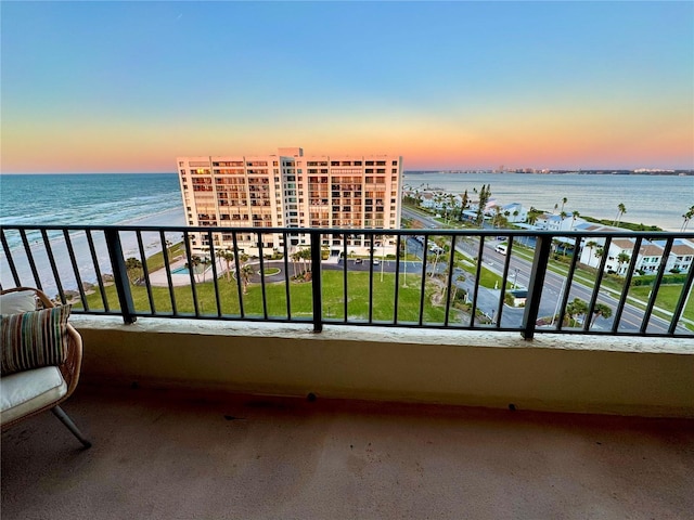 balcony at dusk with a water view and a beach view