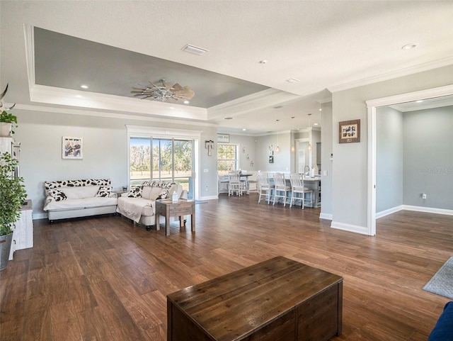 living room with dark hardwood / wood-style flooring, crown molding, and a tray ceiling