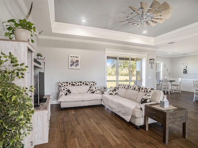 living room featuring ceiling fan, dark hardwood / wood-style flooring, ornamental molding, and a tray ceiling