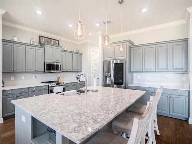 kitchen featuring decorative light fixtures, stainless steel appliances, a kitchen island with sink, and dark hardwood / wood-style floors