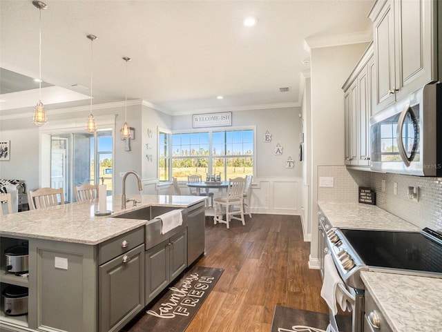 kitchen with sink, stainless steel appliances, pendant lighting, gray cabinets, and a center island with sink