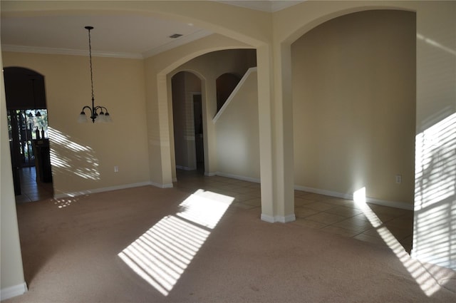 spare room featuring carpet flooring, a chandelier, and ornamental molding