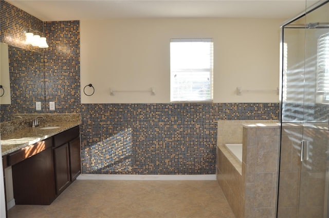 bathroom with tile patterned flooring, vanity, tile walls, and independent shower and bath