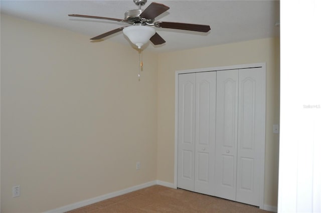 unfurnished bedroom featuring ceiling fan, light carpet, and a closet