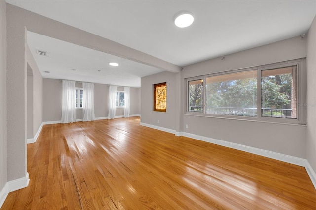 spare room featuring beam ceiling and light wood-type flooring