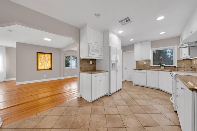 kitchen with white appliances, light tile patterned floors, tasteful backsplash, white cabinetry, and extractor fan