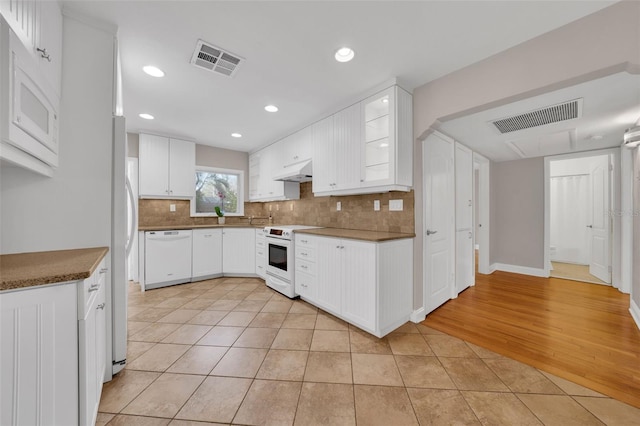 kitchen with tasteful backsplash, white cabinetry, light tile patterned flooring, and white appliances