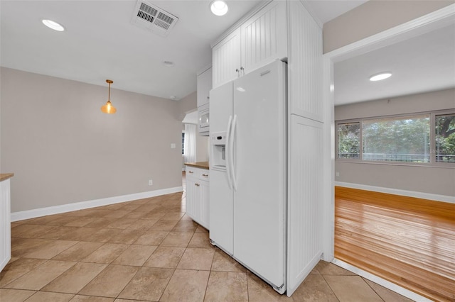 kitchen featuring pendant lighting, white cabinetry, light tile patterned flooring, and white fridge with ice dispenser