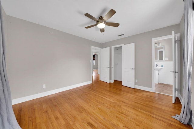 unfurnished bedroom featuring a spacious closet, ceiling fan, light wood-type flooring, and a closet