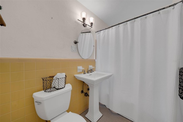 bathroom featuring tile patterned flooring, toilet, tile walls, and sink