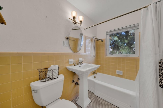 full bathroom with sink, tile patterned floors, toilet, shower / bath combo with shower curtain, and tile walls