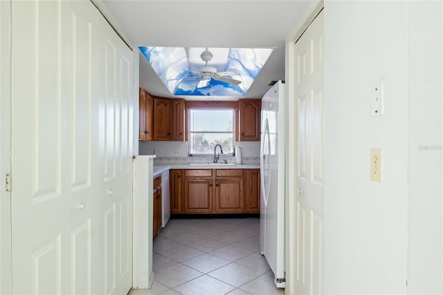 4859 Independence Dr, Bradenton, FL 34210 - kitchen with light countertops, a sink, freestanding refrigerator, light tile patterned floors, and brown cabinets