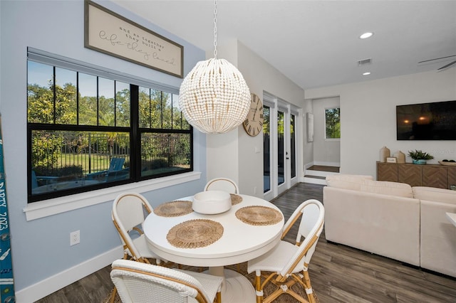 dining space featuring ceiling fan with notable chandelier, dark hardwood / wood-style flooring, and plenty of natural light