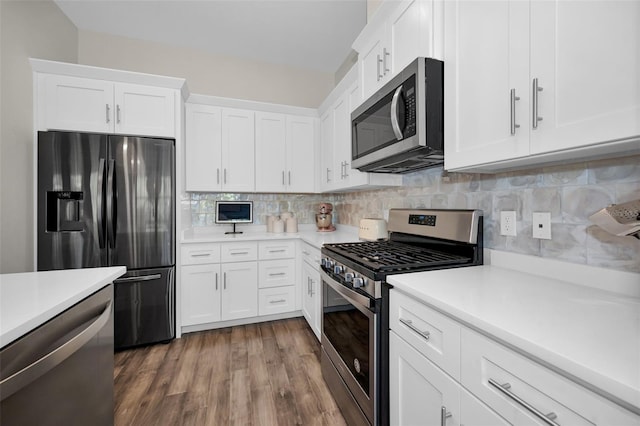 kitchen featuring tasteful backsplash, white cabinetry, stainless steel appliances, and hardwood / wood-style flooring