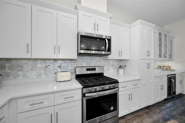 kitchen with white cabinetry, beverage cooler, dark hardwood / wood-style floors, backsplash, and appliances with stainless steel finishes