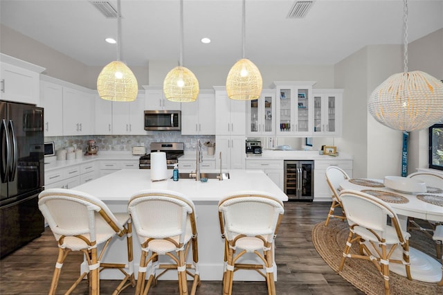 kitchen with white cabinets, pendant lighting, beverage cooler, and stainless steel appliances