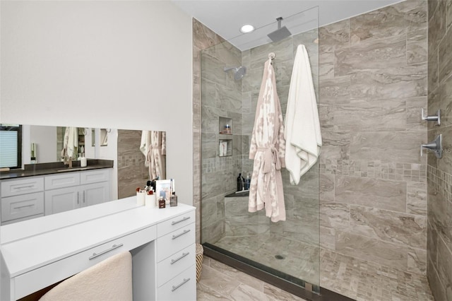 bathroom featuring tiled shower and vanity