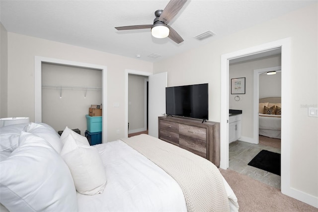 carpeted bedroom with ensuite bath, ceiling fan, and a closet