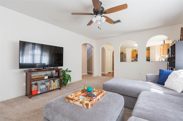 living room featuring light carpet, a textured ceiling, and ceiling fan