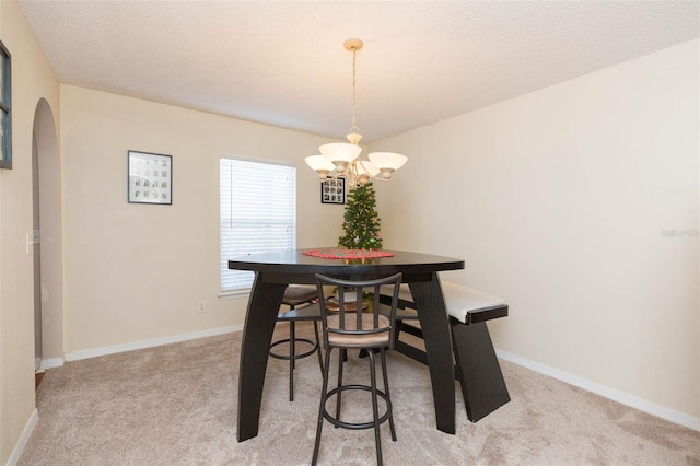 dining space with light carpet, a textured ceiling, and a notable chandelier