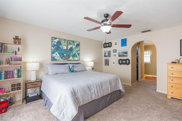 bedroom featuring a textured ceiling, ceiling fan, and light carpet