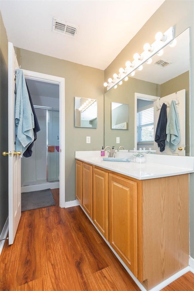 bathroom with hardwood / wood-style flooring, vanity, and walk in shower