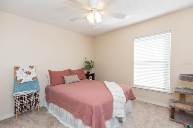 carpeted bedroom with a textured ceiling, multiple windows, and ceiling fan