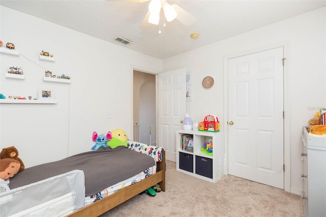 carpeted bedroom with ceiling fan and a textured ceiling