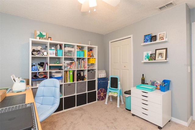 recreation room with light carpet, a textured ceiling, and ceiling fan