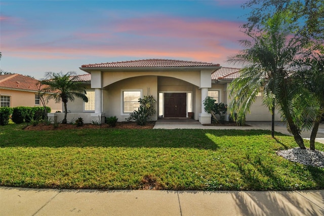 mediterranean / spanish-style home with a yard and a garage