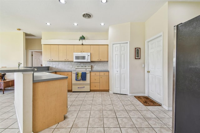 kitchen with kitchen peninsula, light brown cabinetry, tasteful backsplash, white appliances, and light tile patterned floors