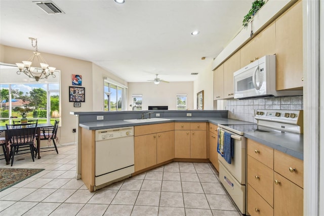 kitchen with kitchen peninsula, white appliances, ceiling fan with notable chandelier, sink, and light tile patterned flooring