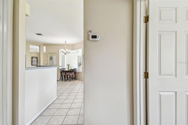 corridor featuring light tile patterned floors and a notable chandelier