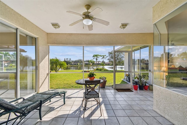 sunroom with a wealth of natural light, a water view, and ceiling fan