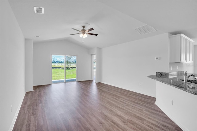 unfurnished living room with ceiling fan, sink, dark wood-type flooring, and vaulted ceiling