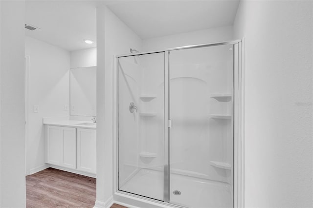 bathroom featuring hardwood / wood-style floors, vanity, and a shower with door