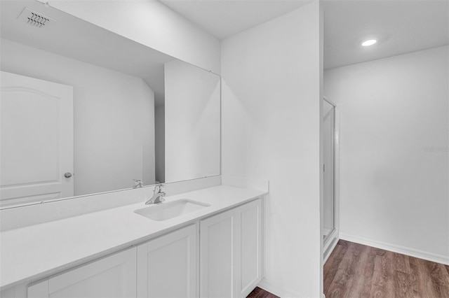 bathroom with wood-type flooring, vanity, and a shower with door