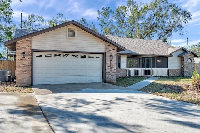 ranch-style home featuring a porch, a garage, and central air condition unit