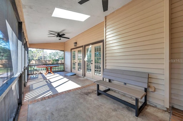 unfurnished sunroom with ceiling fan and vaulted ceiling with skylight