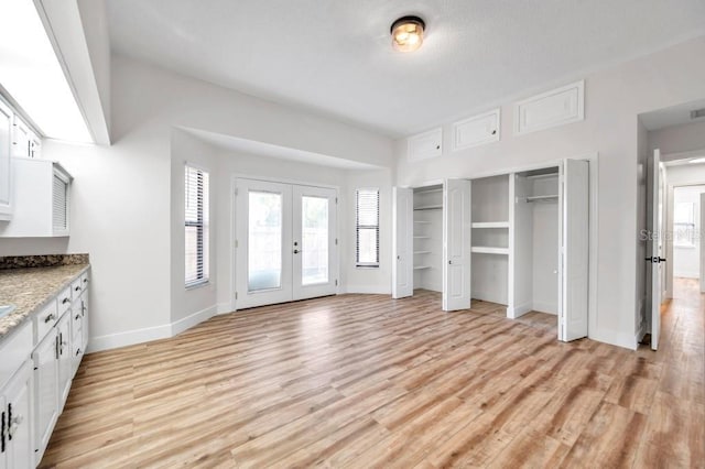 unfurnished bedroom with french doors and light hardwood / wood-style floors