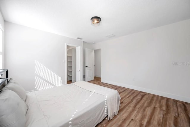 bedroom featuring wood-type flooring, a walk in closet, and a closet