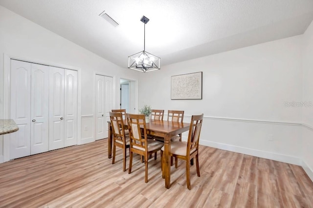 dining area featuring an inviting chandelier, light hardwood / wood-style flooring, and lofted ceiling