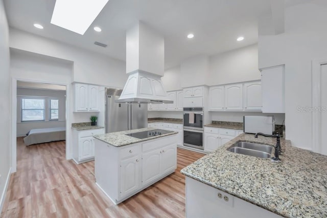 kitchen featuring white cabinets, a skylight, stainless steel appliances, and sink