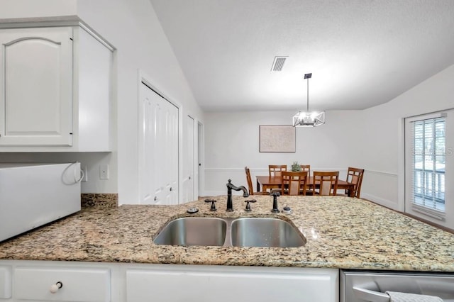 kitchen with dishwasher, sink, decorative light fixtures, lofted ceiling, and white cabinets