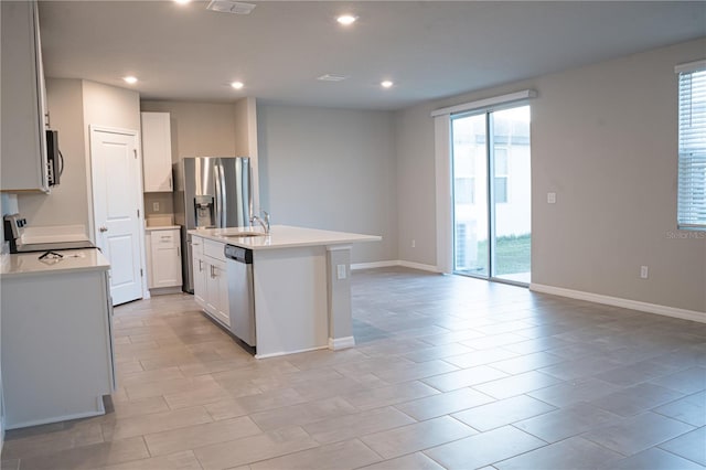 kitchen featuring white cabinetry, a kitchen island with sink, plenty of natural light, and stainless steel appliances