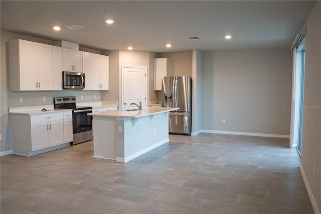 kitchen with appliances with stainless steel finishes, a center island with sink, white cabinetry, and sink