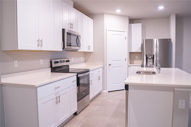 kitchen with white cabinets, sink, stainless steel appliances, and a kitchen island with sink