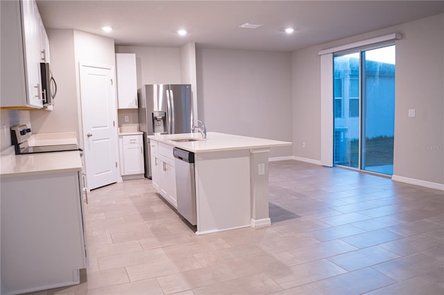 kitchen featuring appliances with stainless steel finishes, sink, white cabinets, an island with sink, and light tile patterned flooring