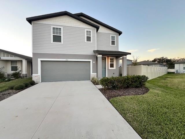 traditional-style home featuring a front lawn, driveway, fence, a garage, and stucco siding