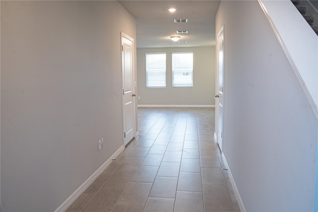 corridor featuring light tile patterned flooring, visible vents, baseboards, and recessed lighting